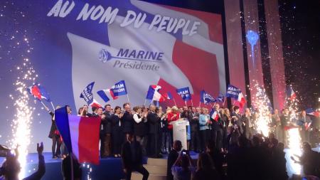 Marine le Pen surrounded by people and flags at a rally in Lille, France