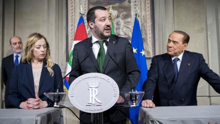 Matteo Salvini at a podium between Silvio Berlusconi and interpreter