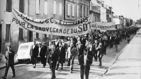 Group of people holding large signs marching in a street