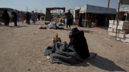 Image of person crouched on ground in UNHCR refugee camp